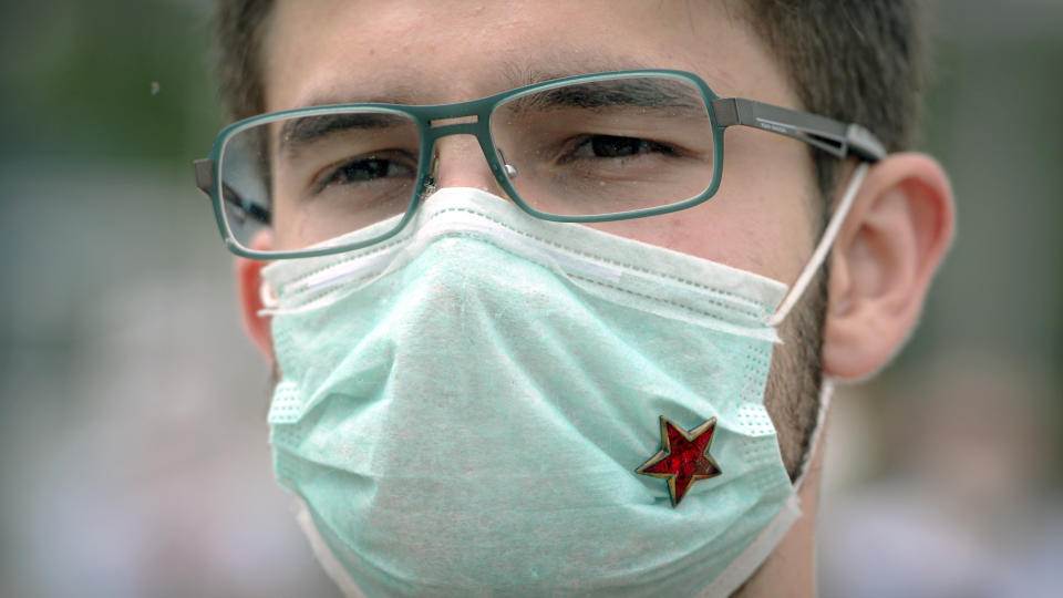 A youngster wearing a surgical mask decorated with the Yugoslav communist partisan red star participates in an anti-Nazi protest outside the Sacred Heart Cathedral during a mass commemorating members of the pro-Nazi Croatian WWII Ustasha regime, responsible for sending tens of thousands of Serbs, Gypsies and Jews to their death in concentration camps, who were killed at the end of WWII by Yugoslav communist troops, in Sarajevo, Bosnia, Saturday, May 16, 2020. Bosnian Catholic clerics along with Croatian state representatives and members of the Bosnian Croats community attended a religious service commemorating the massacre of Croatian pro-Nazis by victorious communists at the end of World War II. (AP Photo/Kemal Softic)