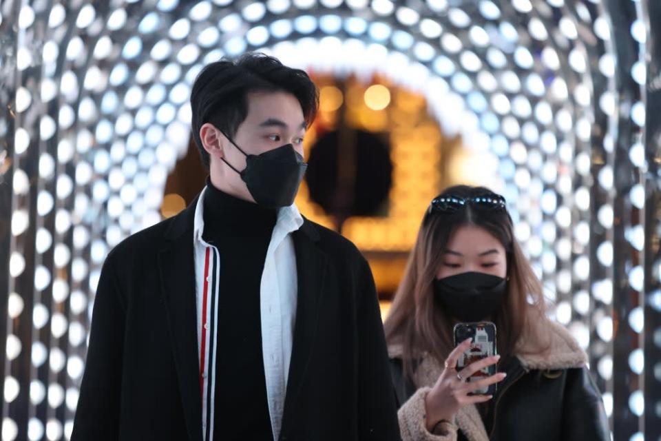 People wearing face masks walk through a Christmas-themed arch in Covent Garden (James Manning/PA) (PA Wire)