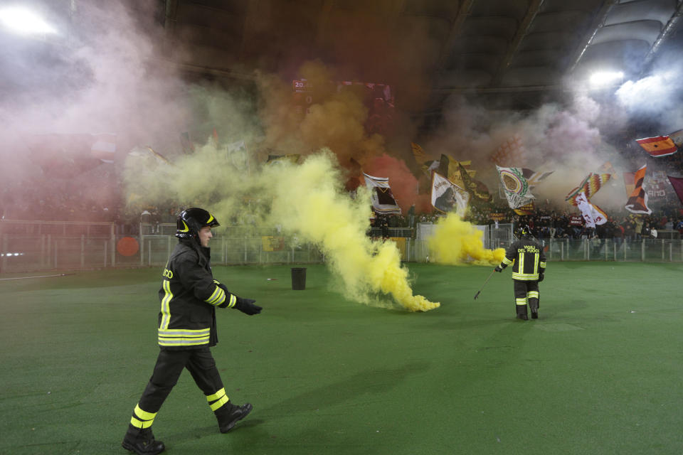 Firefighters arrive to remove flares prior to the start of a Serie A soccer match between AS Roma and Torino, at Rome's Olympic Stadium, Tuesday, March 25, 2014. (AP Photo/Andrew Medichini)