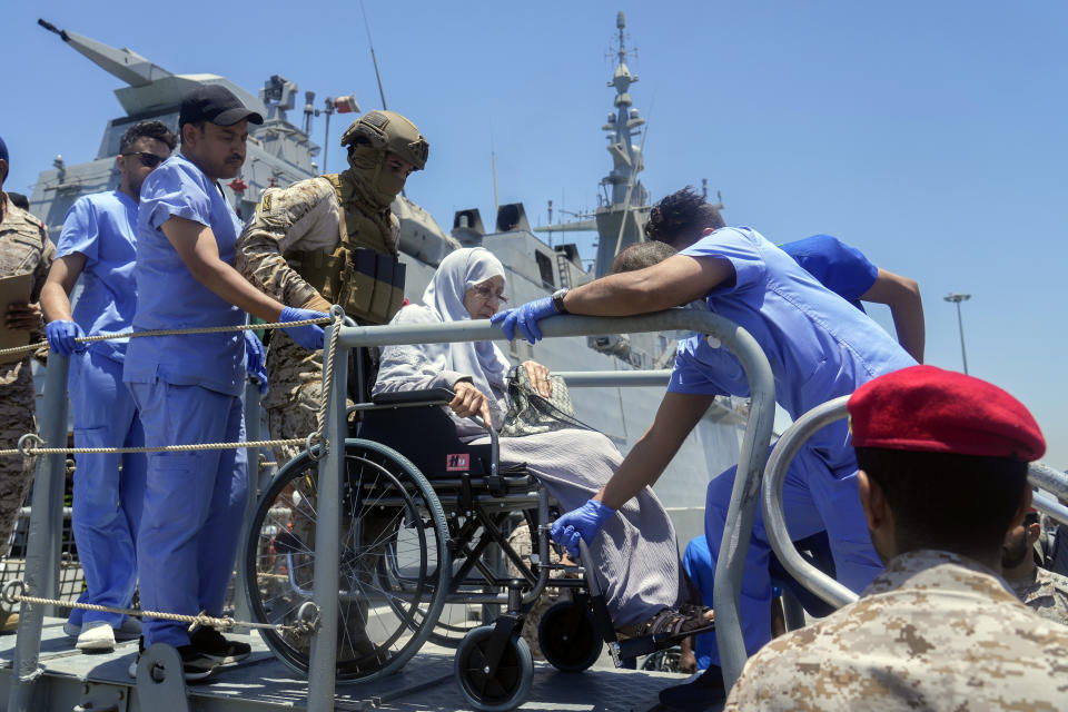 Saudi commandos carry a wheelchair Saudi evacuee as she arrive at Jeddah port, Saudi Arabia, Wednesday, May 3, 2023. Exhausted Sudanese and foreigners joined growing crowds at Sudan's main seaport Tuesday, waiting to be evacuated from the chaos-stricken nation. After more than two weeks of fighting, areas of the capital of Khartoum appear increasingly abandoned. (AP Photo/Amr Nabil)