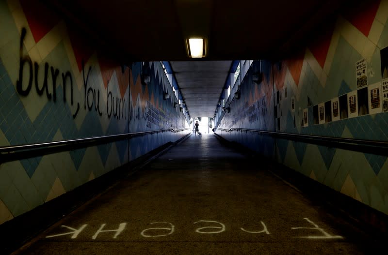 A man walks past anti-government posters and graffiti at a underground passage in Hong Kong