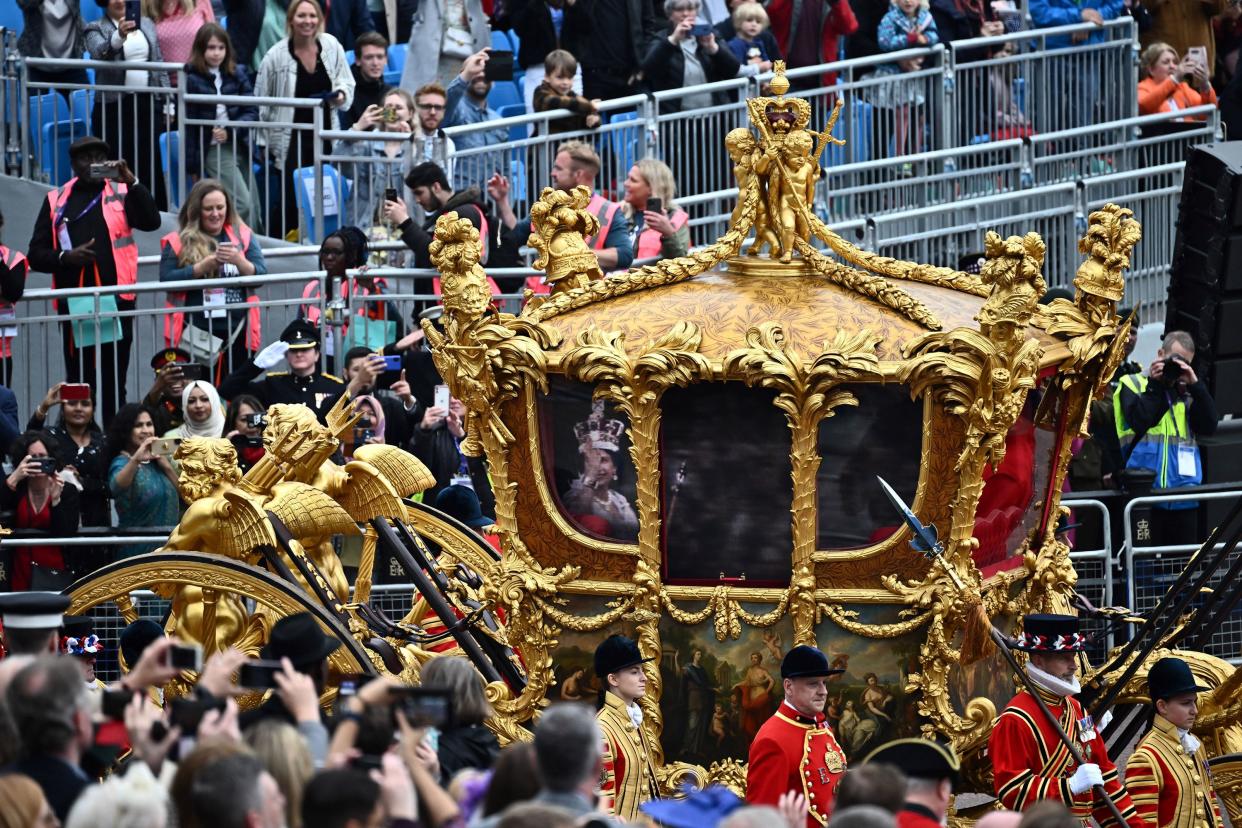 Attendees take pictures of the hologram of Britain's Queen Elizabeth II projected on the Gold State Coach during the Platinum Jubilee Pageant outside Buckingham Palace in London on Sunday, June 5, 2022.