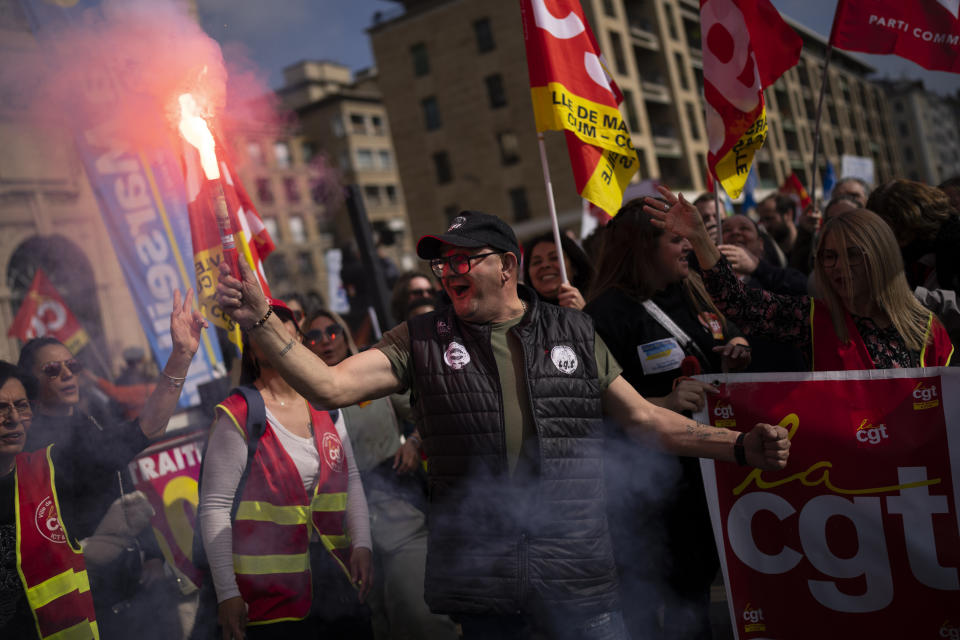 A protester holds a flare during a demonstration in Marseille, southern France, Tuesday, March 7, 2023. Garbage collectors, utility workers and train drivers are among people walking off the job Tuesday across France. They are expressing anger at a bill raising the retirement age to 64, which unions see as a broader threat to the French social model. (AP Photo/Daniel Cole)