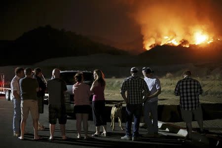 Residents watch a fast-moving wildfire approach in San Marcos, California May 14, 2014. REUTERS/Sandy Huffaker