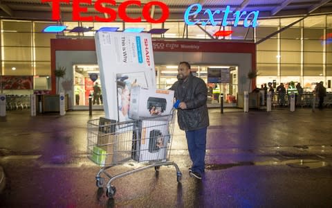 People leave Tesco superstore in Wembley in the early morning after shopping for Black Friday deals. 