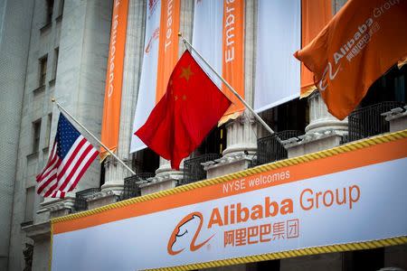 The Chinese (C) and U.S. (R) flags fly over signs of Alibaba Group Holding Ltd hung on the facade in front of the New York Stock Exchange before the company's initial public offering (IPO) under the ticker "BABA" in New York September 19, 2014. REUTERS/Lucas Jackson