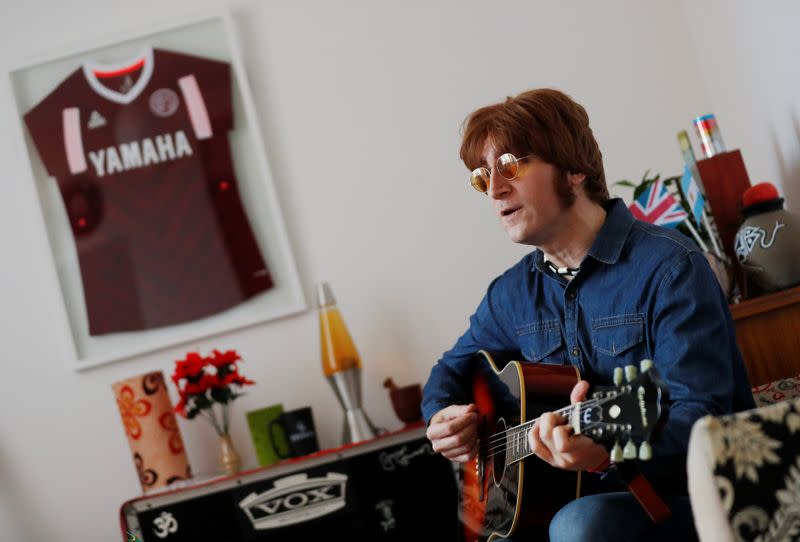 Javier Parisi, who impersonates late former Beatle John Lennon, plays the guitar during an interview with Reuters, in Lanus, on the outskirts of Buenos Aires