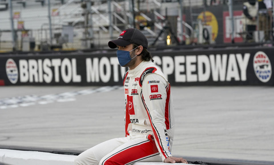 Daniel Suarez sits on a wall along pit row as he waits for driver introductions for the NASCAR Cup Series auto race Saturday, Sept. 19, 2020, in Bristol, Tenn. (AP Photo/Steve Helber)