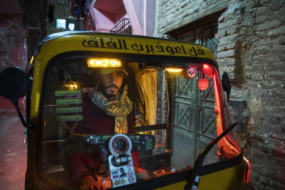 In this Nov. 19, 2019 photo, a driver maneuvers his tuk-tuk in a narrow alleyway of a slum in Cairo, Egypt. Motorized rickshaws known as tuk-tuks have ruled the streets of Cairo’s slums for the past two decades hauling millions of Egyptians home every day. Now the government is taking its most ambitious stand yet against the polluting three-wheeled vehicles: to modernize the neglected transport system, it plans to replace tuk-tuks with clean-running minivans. (AP Photo/Nariman El-Mofty)