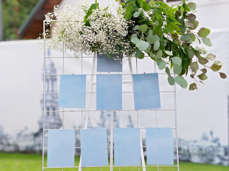wedding seating chart on a stand with greenery on top