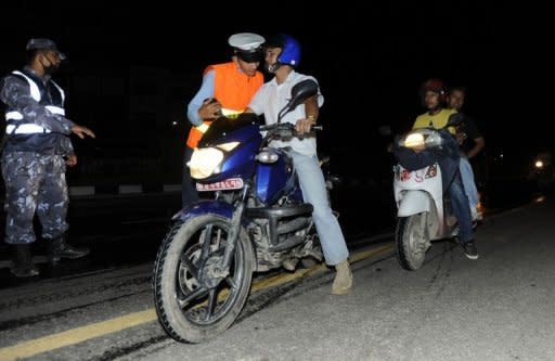 A Nepalese traffic policeman (2nd L), seen leaning over to smell the breath of a motorcyclist to determine the level of his alcohol consumption at a roadblock in Kathmandu. With breathalysers scarce and blood tests unavailable, the method for catching lawbreakers in Kathmandu is primitive as police officers simply stop drivers and engage them in conversation