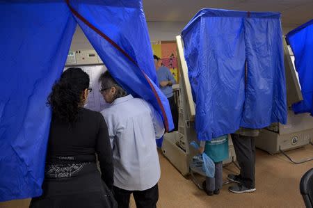 FILE PHOTO: An election worker helps a voter use the voting machine during the U.S. presidential election in Philadelphia, Pennsylvania, U.S. November 8, 2016. REUTERS/Charles Mostoller