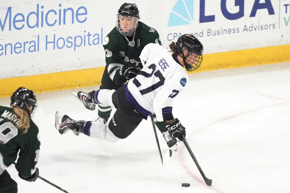 Minnesota forward Taylor Heise, front, and Boston defender Kaleigh Fratkin, behind, pursue the puck during the first period of Game 1 of a PWHL hockey championship series Sunday, May 19, 2024, in Lowell, Mass. (AP Photo/Steven Senne)