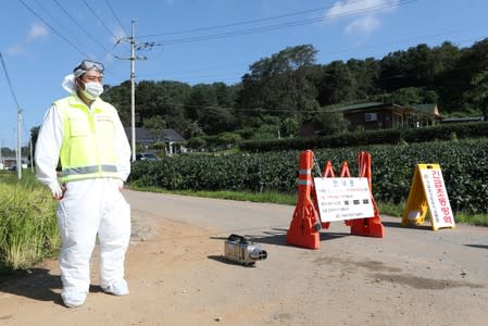 A quarantine official wearing protective gear stands guard near a pig farm involved in African swine fever in Yeoncheon