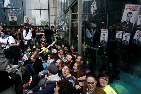 Environmental activists block the entrance of the French bank Societe Generale headquarters during a "civil disobedience action" to urge world leaders to act against climate change, in La Defense near Paris, France, April 19, 2019. The slogan reads " Macron, President of polluters". REUTERS/Benoit Tessier