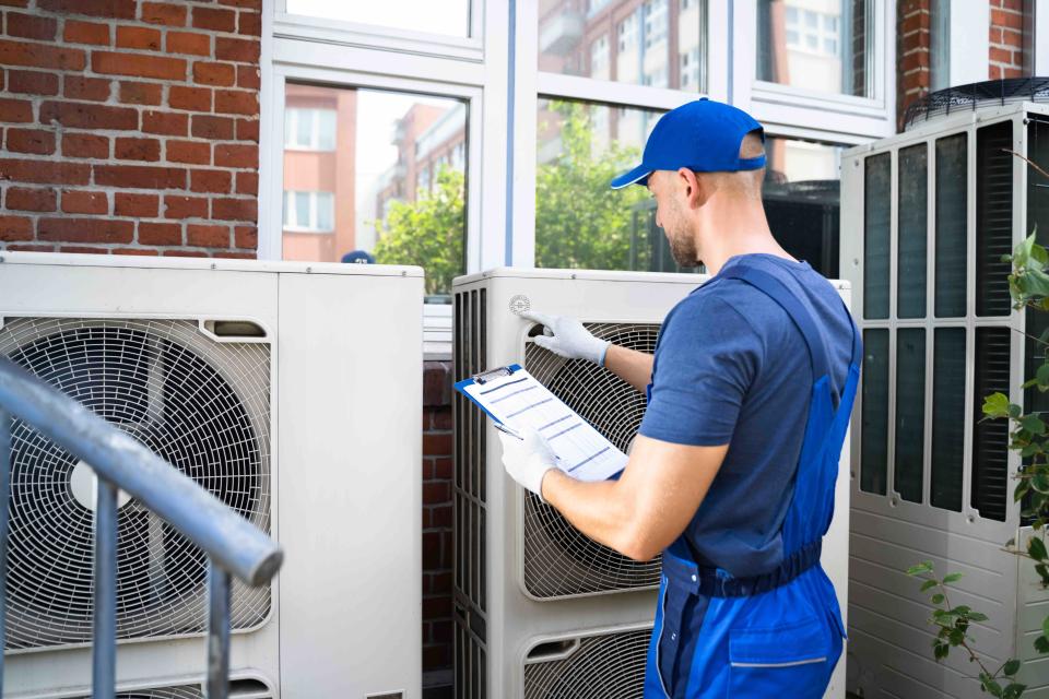 HVAC Technician Checking Units Outside House