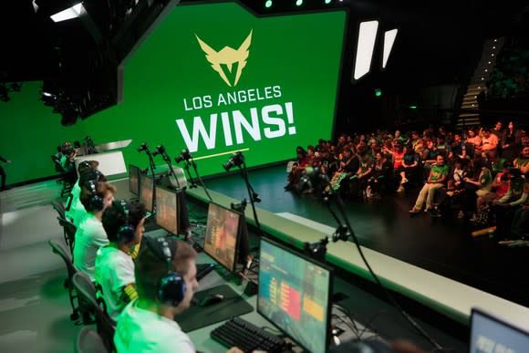 Members of the Overwatch League team Los Angeles Valiant sitting at computers with a sign reading "Los Angeles wins!"