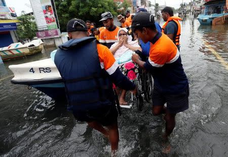 Sri Lankan navy personnel carry a woman on a wheelchair on a flooded road in Wellampitiya, Sri Lanka May 21, 2016. REUTERS/Dinuka Liyanawatte