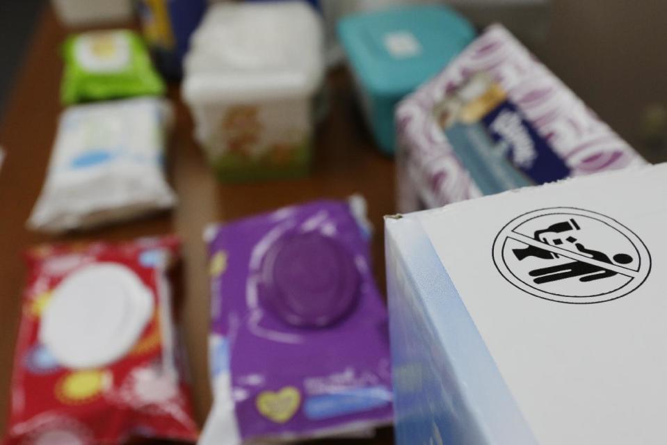 In this photograph taken, Friday, Sept. 20, 2013, in Middlesex, N.J., the label that indicates wipes should not be flushed in a toilet is seen on a box next to baby wipes at the office of Rob Villee, executive director of the Plainfield Area Regional Sewer Authority in New Jersey. Increasingly popular bathroom wipes, thick, premoistened towelettes that are advertised as flushable, are creating clogs and backups in sewer systems around the nation. The problem has gotten so bad in this upstate New York town that frustrated sewer officials traced the wipes back to specific neighborhoods, and even knocked on doors to break the embarrassing news to residents that they are the source of a costly, unmentionable mess. An industry trade group this month revised its guidelines on which wipes can be flushed, and has come out with a universal stick-figure, do-not-flush symbol to put on packaging. (AP Photo/Julio Cortez)