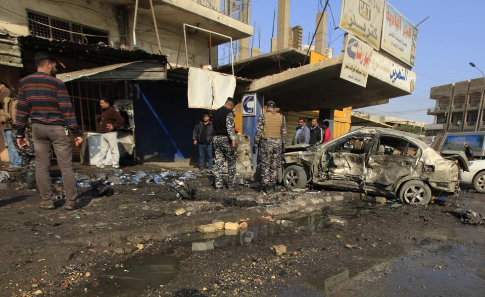Policemen look at the site of a car bomb attack in Baghdad, January 15, 2014. Bomb attacks hit the Iraqi capital Baghdad and a village near the northern town of Baquba on Wednesday, killing at least 52 people, police and hospital sources said. (REUTERS/Ahmed Saad)