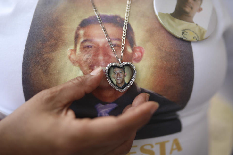 The mother of Luis Arroyo Ruiz, who disappeared in Jan. 2018, wears a pendant with his photograph during a Mass at the site where almost 300 human remains were found in Colinas de Santa Fe, Mexico, Monday, Oct. 15, 2018. The Mass was held one day before the Solecito Collective is honored by Notre Dame University for their work locating the remains of missing people in Veracruz state. The Solecito Collective is made up people searching for their missing loved ones. (AP Photo/Felix Marquez)