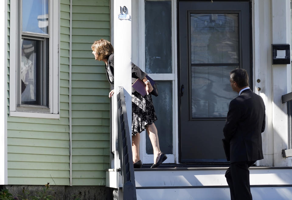 Carrie Sideris, of Newton, Mass., talks to a resident through a window accompanied by her husband, Dan Sideris, as they return to door-to-door visits as Jehovah's Witnesses, Thursday, Sept. 1, 2022, in Boston. Even in pre-pandemic times, door-knocking ministry came with anxiety because Witnesses never knew how they would be received at any given home. In 2022 that’s even more the case, and evangelizers are being advised to be mindful that lives and attitudes have changed. (AP Photo/Mary Schwalm)