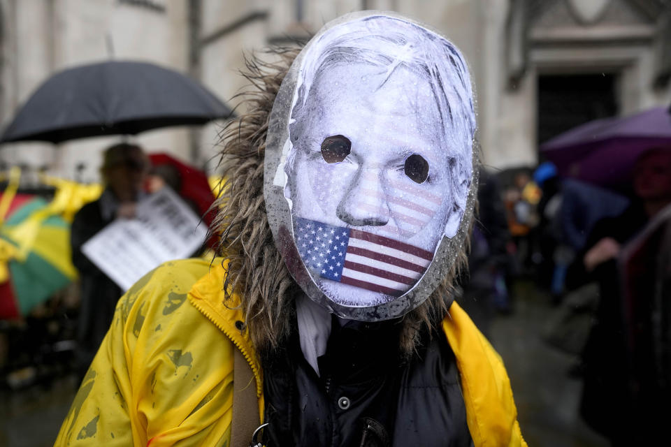 A protester wearing a mask stands at the Royal Courts of Justice entrance in London, Wednesday, Feb. 21, 2024. Julian Assange's lawyers are on their final U.K. legal challenge to stop the WikiLeaks founder from being sent to the United States to face spying charges. The 52-year-old has been fighting extradition for more than a decade, including seven years in self-exile in the Ecuadorian Embassy in London and the last five years in a high-security prison. (AP Photo/Alastair Grant)