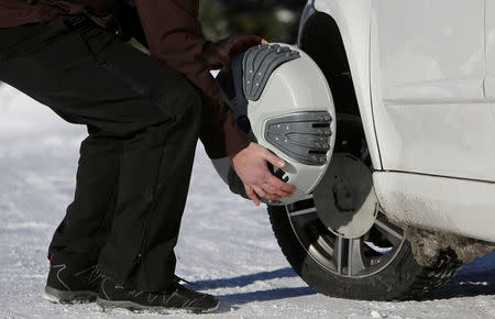 A man puts automatic snow chains on a car tire at the ski resort Ovcarna near the village of Karlova Studanka, Czech Republic, January 19, 2017. REUTERS/David W Cerny