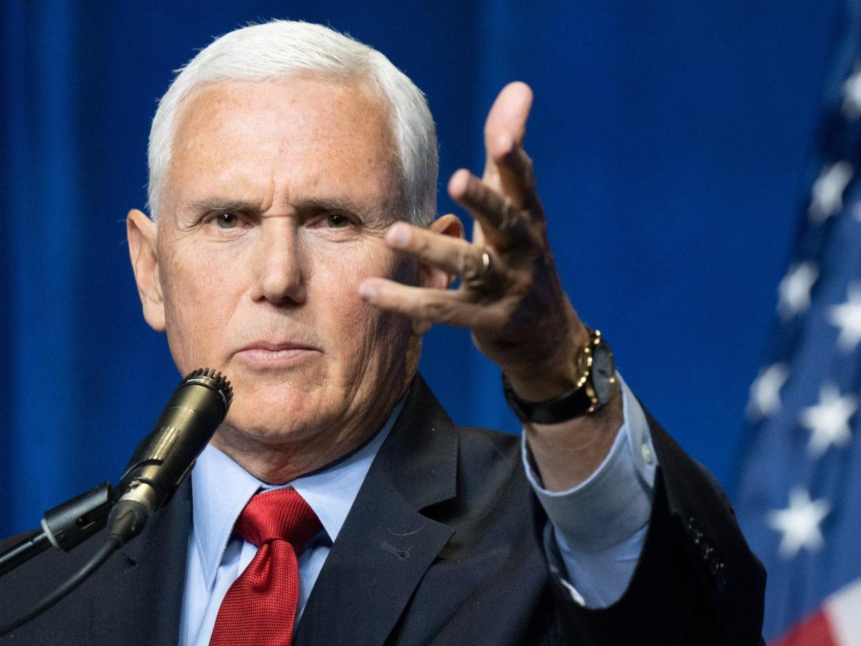 Former Vice President Mike Pence gestures forward with his open left hand tilted sideways.