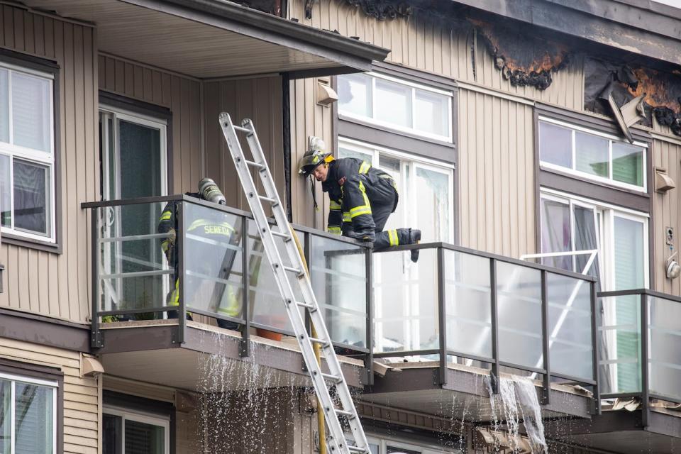 Abbotsford fire crews stand on the balconies of an Abbotsford apartment building as they try to contain a three-alarm fire.