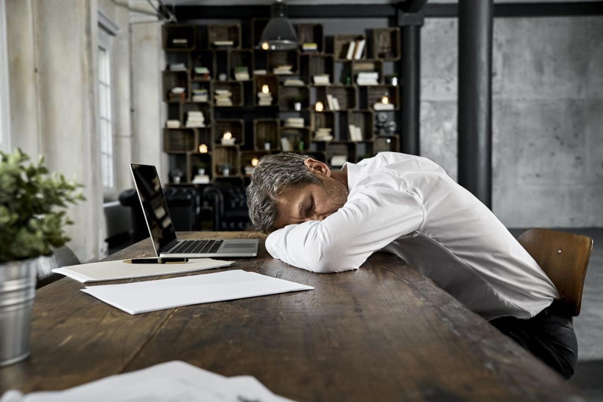 mature businessman sleeping on desk in loft