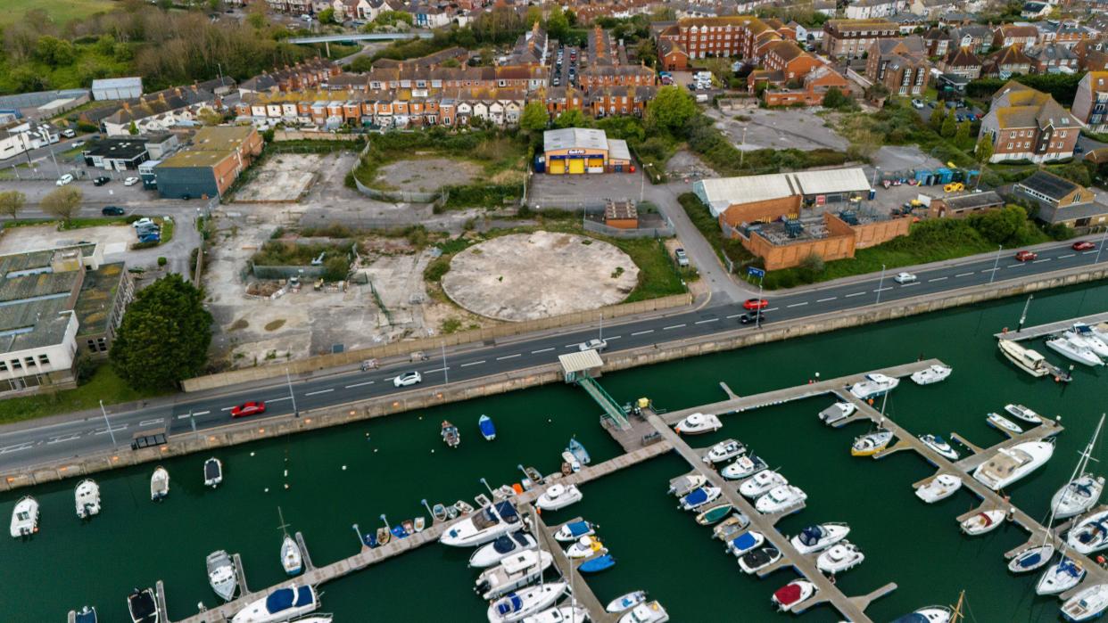 Aerial view of development land next to a road and a marina full of small boats