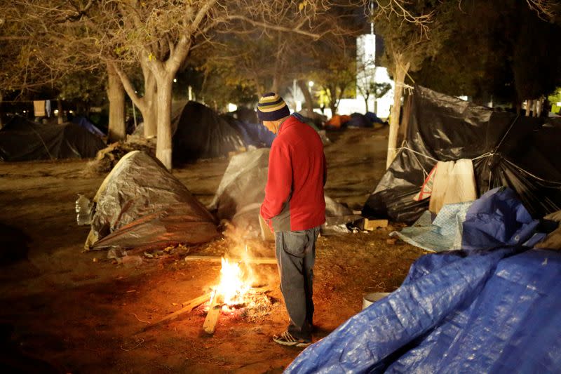 FOTO DE ARCHIVO: Un hombre acampando en Ciudad Juárez mientras espera para solicitar una visa en EEUU calentándose junto a una fogata