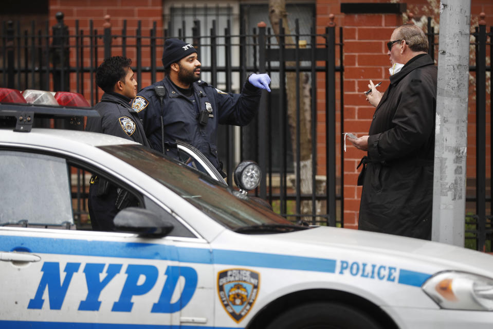 Funeral director Tom Cheeseman, right, speaks to police officers before making a house call to collect a body, Friday, April 3, 2020, in the Brooklyn borough of New York. (AP Photo/John Minchillo)