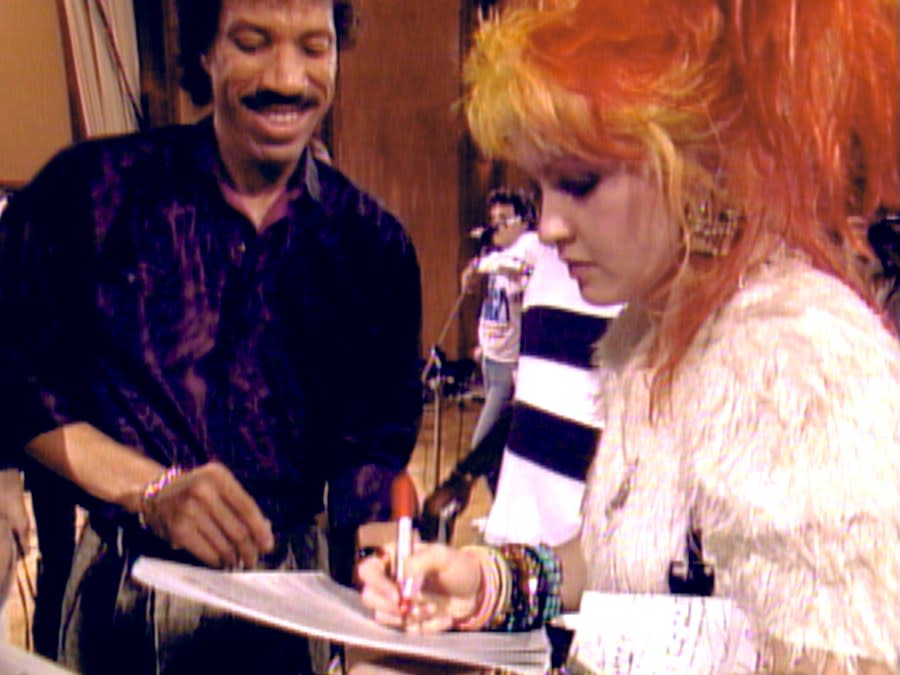 This image released by Netflix shows Lionel Richie, left, and Cyndi Lauper in a scene from “The Greatest Night in Pop.” (Netflix via AP)