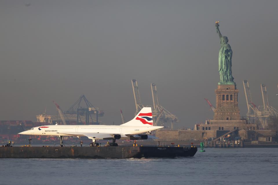 A retired British Airways Concorde supersonic airliner is moved by a barge past the Statue of Liberty on the Hudson River on March 14, 2024 in New York City.