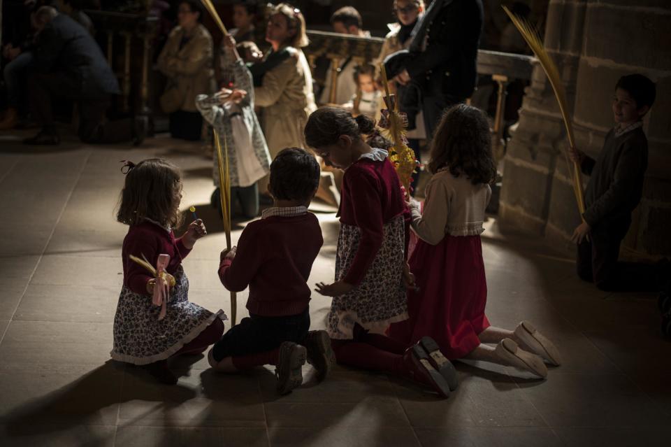 EDS NOTE : SPANISH LAW REQUIRES THAT THE FACES OF MINORS ARE MASKED IN PUBLICATIONS WITHIN SPAIN. Several children hold palms tree during Palm Sunday, prior to Spain Holy Week, in Pamplona, northern Spain, Sunday April 13, 2014. Spanish devoted Catholics take part on a lot of religious ceremonies during Holy Week. (AP Photo/Alvaro Barrientos)