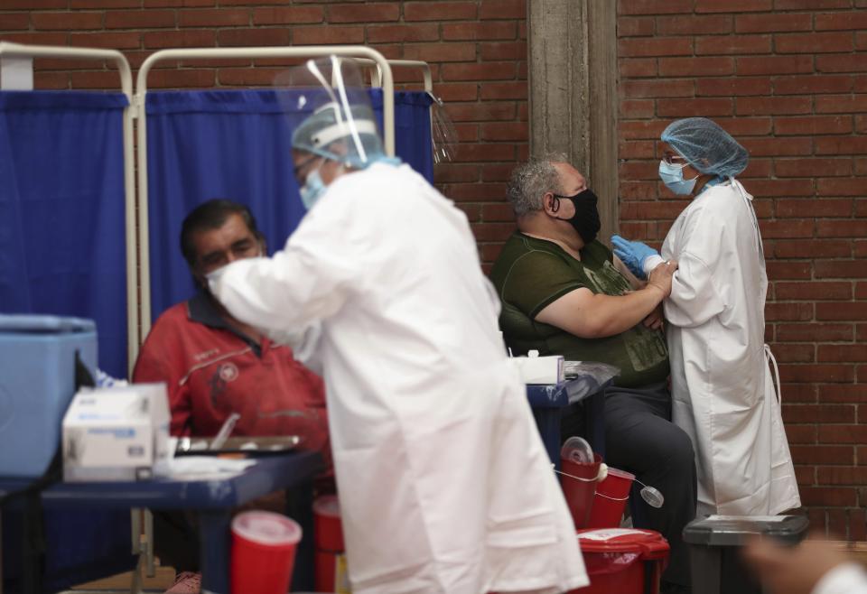 Nurses talk with people before giving a first dose of China's Sinovac vaccine for COVID-19 at a gym in Bogota, Colombia, Friday, June 4, 2021. (AP Photo/Fernando Vergara)