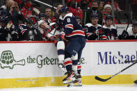 Washington Capitals left wing Alex Ovechkin (8) checks Columbus Blue Jackets defenseman Andrew Peeke (2) into the Capitals' bench area during the second period of an NHL hockey game, Saturday, Dec. 4, 2021, in Washington. (AP Photo/Nick Wass)