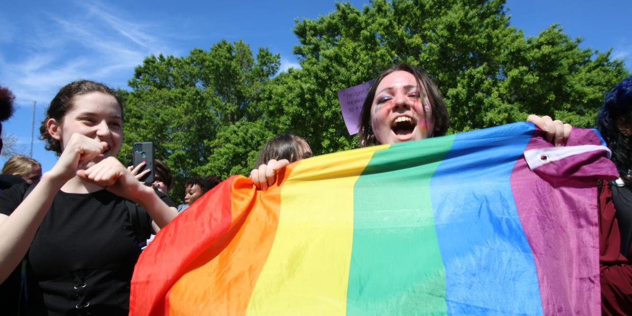 A high school student holds a Pride flag.