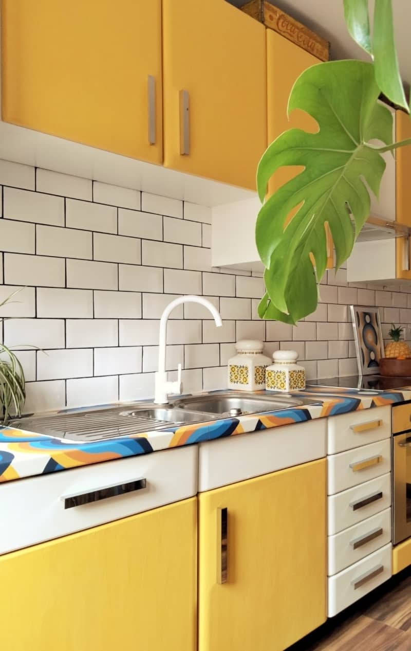 Kitchen with yellow and cabinet doors and tile backsplash.