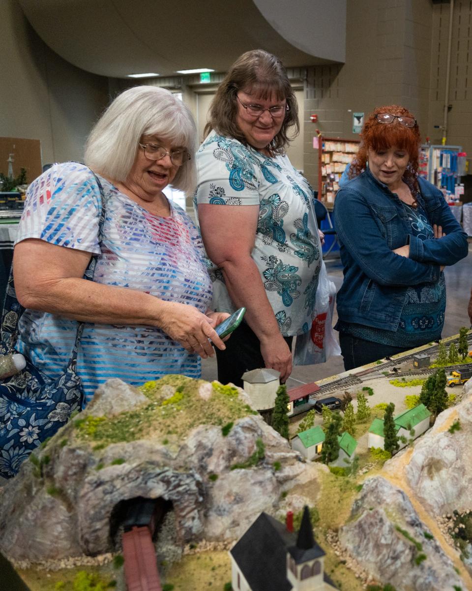 Train show attendees take a look at the Austin Model Railway Society's raffle model railway, modeled after a mining town, while browsing at the Austin 2023 Train Show in the Palmer Events Center, May 6, 2023. The model, which features a mine, a church, an ice cream vendor, a pond and other details is built by eight AMRS members.