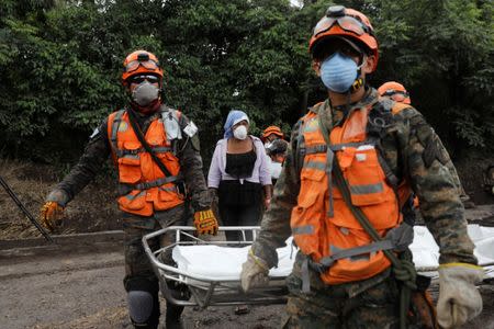 Eufemia Garcia, 48, who lost 50 members of her family during the eruption of the Fuego volcano, observes soldiers carrying human remains found at her house in San Miguel Los Lotes in Escuintla, Guatemala, June 12, 2018. REUTERS/Carlos Jasso