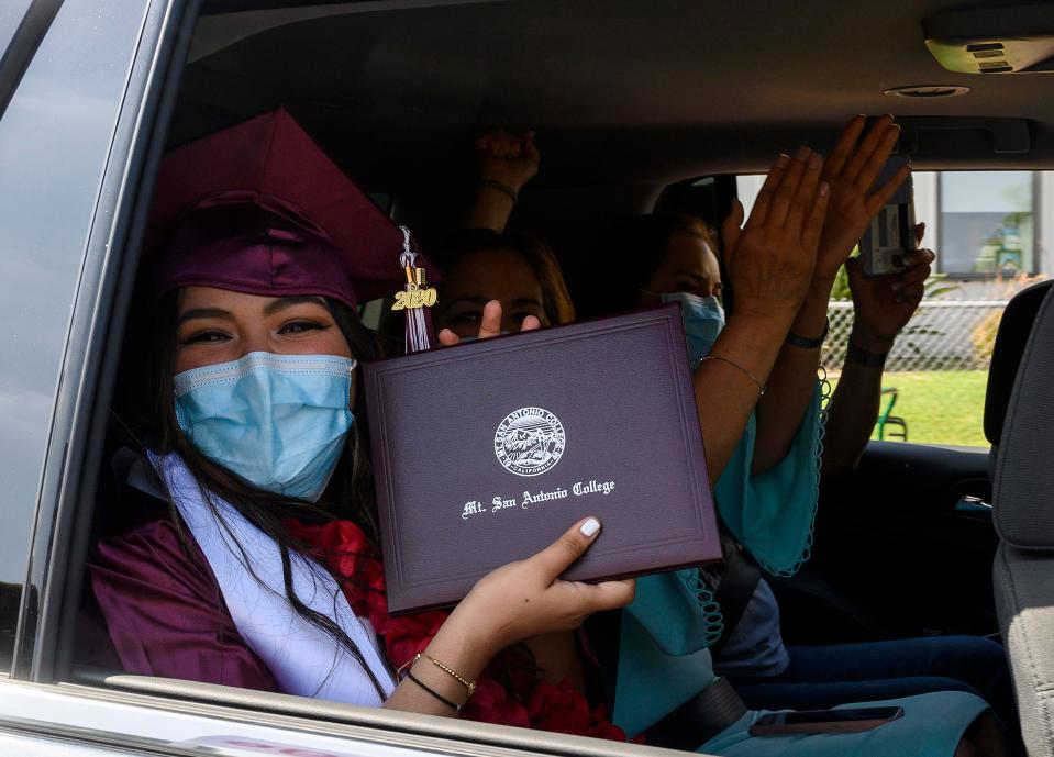 An unidentified graduating student from Mount San Antonio College holds up her diploma while her family members cheer after receiving it at the school's first drive-thru commencement ceremony for the "Resilient Class" of 2020, which includes more than 650 students, June 18, 2020 in Walnut, California. - The college design the car-based ceremony to comply with Los Angeles County and California state COVID-19 gathering restrictions. (Photo by Robyn Beck / AFP) (Photo by ROBYN BECK/AFP via Getty Images)