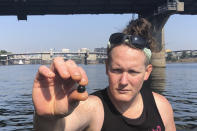 Activist Juniper Simonis holds up an impact munition that Simonis had just found in the sediment of the Willamette River in Portland, Ore., on Oct. 2, 2020. Night after night in Portland, tear gas and other crowd control devices enveloped protesters and bystanders in aerosolized compounds that then settled on the ground and wound up washed into storm drains. Test samples from those storm drains have turned up heavy metals and chemicals at much higher levels than samples collected from control sites elsewhere. (AP Photo/Andrew Selsky)