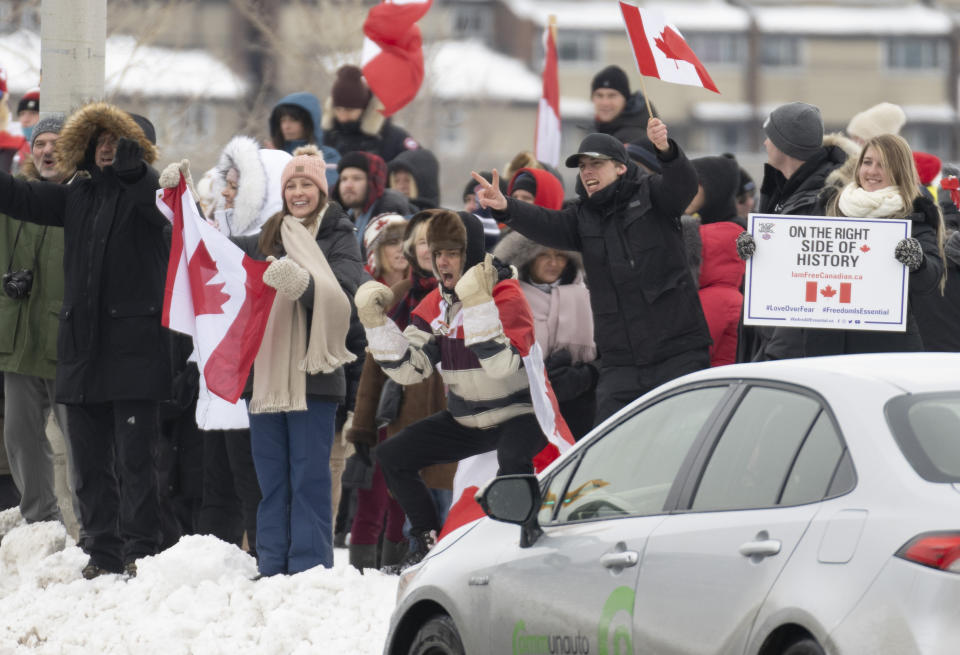 Protesters cheer at cars as they stand on a street corner outside the restricted area in the downtown core, in Ottawa, Sunday, Feb. 20, 2022. (Adrian Wyld/The Canadian Press via AP)