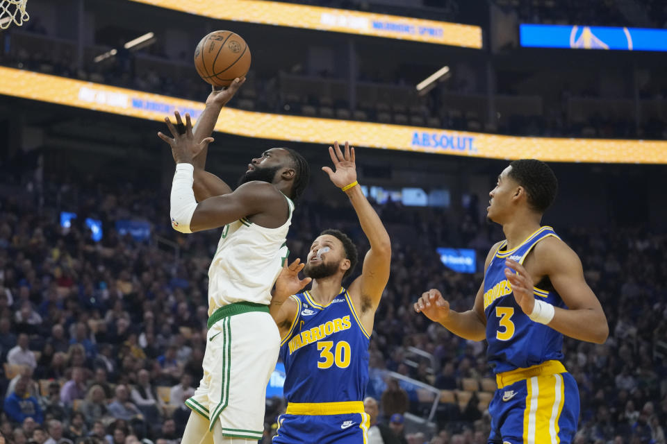 Boston Celtics guard Jaylen Brown, left, shoots next to Golden State Warriors guard Stephen Curry (30) during the first half of an NBA basketball game in San Francisco, Saturday, Dec. 10, 2022. (AP Photo/Godofredo A. Vásquez)