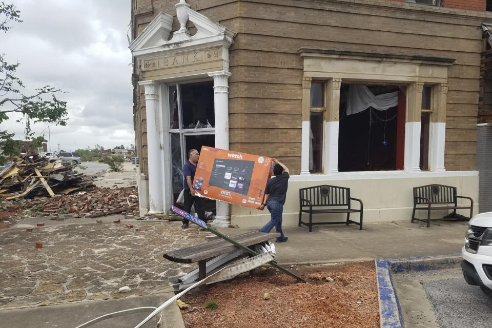 People remove items from a building damaged by a tornado in Sulphur, Okla., Sunday, April 28, 2024. (AP Photo/Ken Miller)