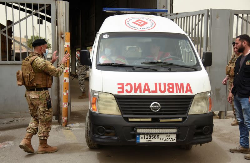 A Lebanese army soldier gestures to health workers inside an ambulance after a boat capsized off the Lebanese coast of Tripoli overnight, at the entrance of port of Tripoli