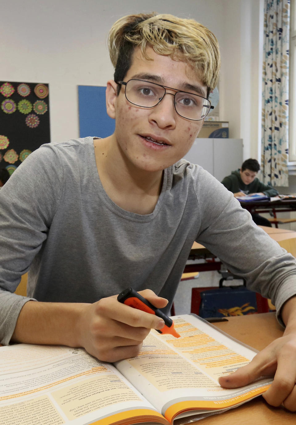 In this Dec. 7, 2018 photo Hassan Husseini from Afghanistan poses for a photograph as he attends a class in a school in Vienna, Austria. Like the nearly 10,000 other school-age children who arrived in Austria during Europe’s largest modern influx of refugees, school is where they must learn to bridge different worlds: one that has shaped their families and identities, and the other where they now hope to prosper in peace. (AP Photo/Ronald Zak)